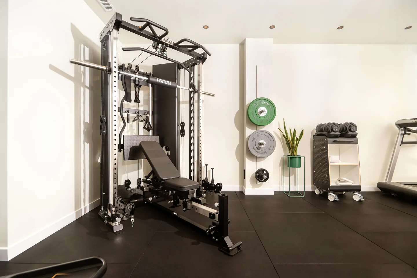 Zona d'entrenament estructural a Local Strength & Pilates amb rack multipower Force USA, banc regulable i manuelles.